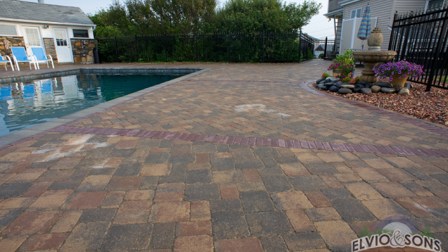 Paver patio with brick accents and bluestone pool coping around in-ground gunite pool.